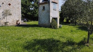 Een gebouw van steen met een kleine toren, omringd door gras en bomen.