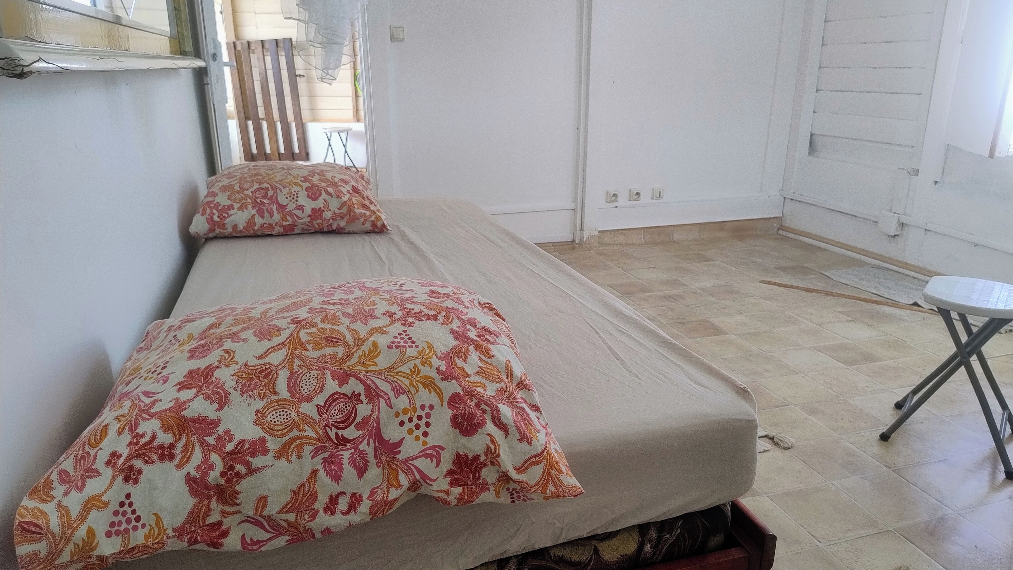 Una habitación con dos camas, una mesita y una puerta.