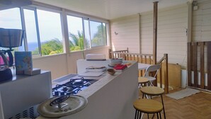 Uma cozinha com fogão a gás, pia e janela com vista para o verde.