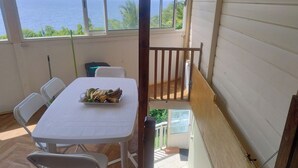 Varanda com mesa posta para dois, uma cadeira e vista para o mar.