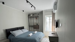 Un dormitorio moderno con una cama, un escritorio y un televisor.