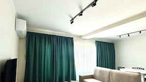 Una sala de estar con un sofá color beige, una mesa de centro blanca y un televisor sobre un mueble de madera.