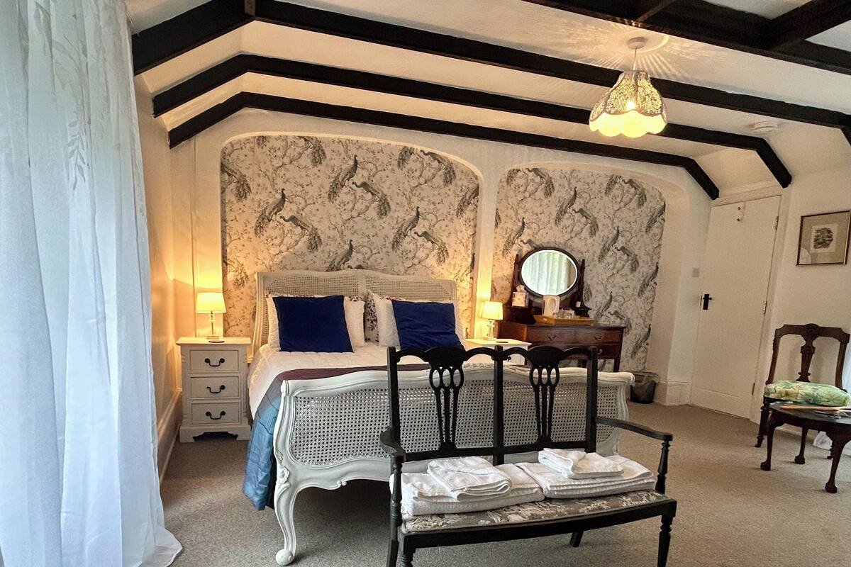 Ein Schlafzimmer mit Bett, Nachttischen, Kommode, Stuhl und Deckenleuchte.