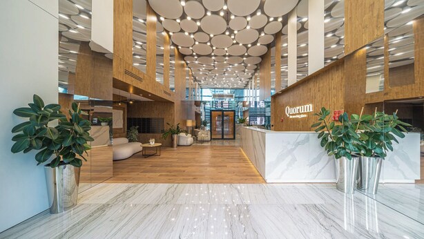 Un lobby moderno con un mostrador de recepción, zona de estar e iluminación circular en el techo.