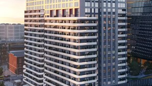 Un edificio moderno de gran altura con varios pisos, amplias ventanas y un patio central con zonas de estar.