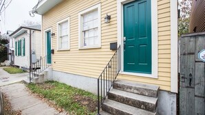 Une maison à deux étages avec un porche à l’avant, une porte verte et une boîte aux lettres.