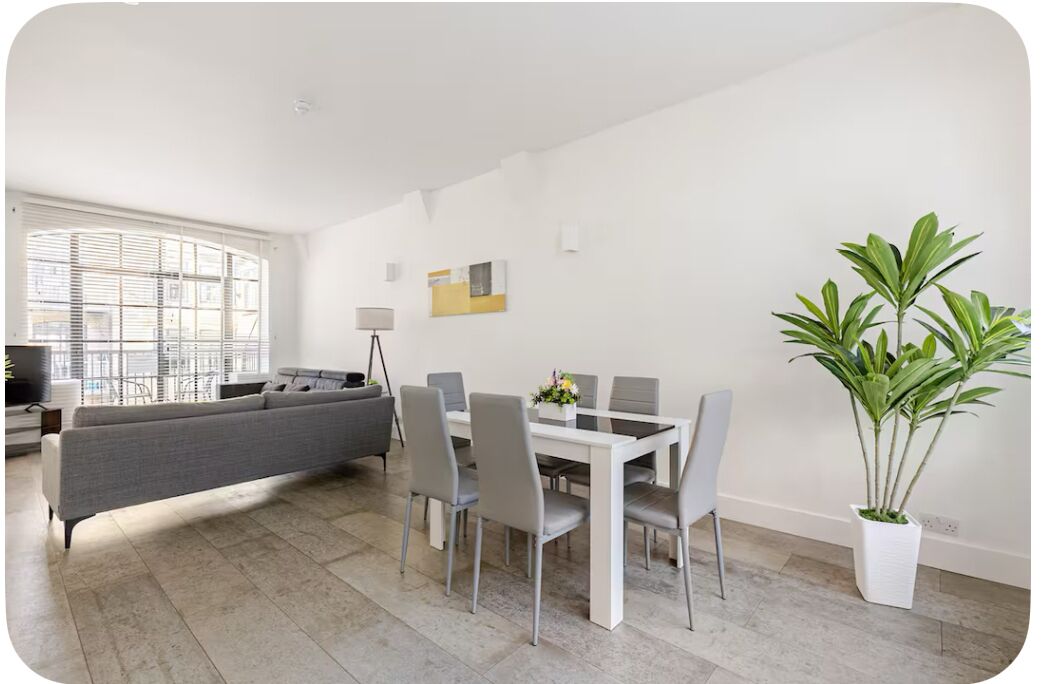 Un salon moderne avec un canapé, une table à manger, des chaises et une plante en pot.