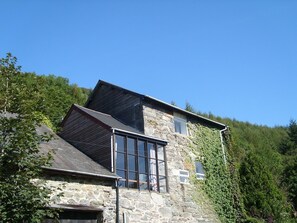A stone building with a sloped roof and large windows.