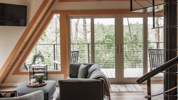 A spacious loft with a high ceiling, a modern staircase, and large windows offering a view of the outdoors. - Riverfront A-Frame Cabin in the Mountains w/ Sauna & Private Hiking Trail (Ellijay)
