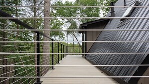 A wooden pedestrian bridge with metal railings, surrounded by trees. - Riverfront A-Frame Cabin in the Mountains w/ Sauna & Private Hiking Trail (Ellijay)