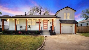 Een huis met twee verdiepingen, een veranda, een garage en een keurig onderhouden gazon.