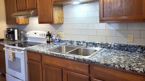 A kitchen with wooden cabinets, a stainless steel sink, a stove, and a coffee maker. - 3bdr Apartment in Museum Hill - #3 (Saint Joseph)