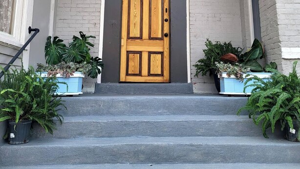 A two-story building with a wooden front door, a small porch, and steps leading up to the entrance. - 3bdr Apartment in Museum Hill - #3 (Saint Joseph)