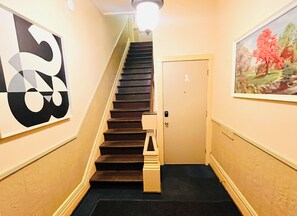 Eine Treppe mit Handlauf, eine Tür am unteren Ende und ein Gemälde an der Wand.