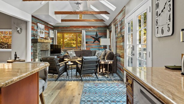 Una cocina moderna con una isla grande, un área de comedor con un sofá y sillas, y un ventanal con una decoración de estrellas en la pared.
