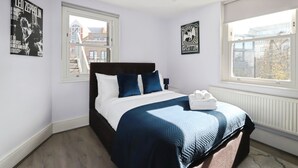 A bedroom with a bed, two posters on the wall, and a window. - Large 3 bedroom apartment in Heart of Theatre District (London)