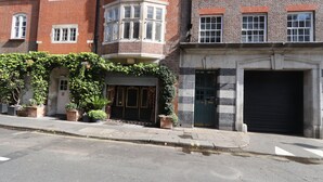 A building with a corner entrance, a garage door, and a bicycle lane. - Large 3 bedroom apartment in Heart of Theatre District (London)