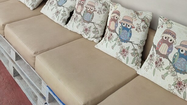 Een muur met een bord met de tekst 'Apartamentos Mirafinca Galapagos' en een zithoek met kussens met uilenmotieven.
