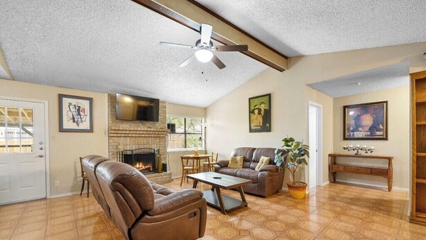 A spacious living room with a fireplace, leather sofas, a dining table, and a ceiling fan. - Private San Antonio Getaway Near SeaWorld! (San Antonio)