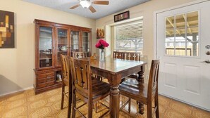 A dining room with a wooden table and chairs, a ceiling fan, a cabinet, and a door with a window. - Private San Antonio Getaway Near SeaWorld! (San Antonio)