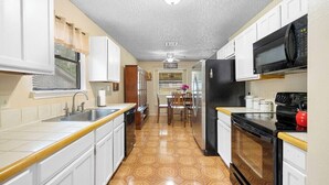 A kitchen with white cabinets, a black refrigerator, a microwave, and a stove. - Private San Antonio Getaway Near SeaWorld! (San Antonio)