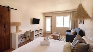Une chambre à coucher avec un lit, un bureau, une chaise, un canapé et un téléviseur.