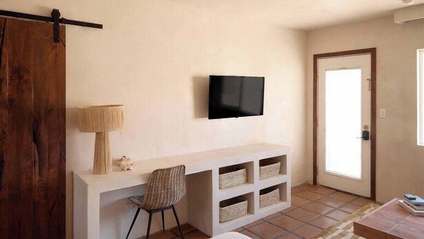 Une chambre à coucher avec un lit, un bureau avec une chaise, une télévision et une porte.