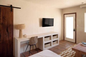 A bedroom with a bed, a desk with a chair, a television, and a door. - Stylish Studio - Walk to the Beach! (Imperial Beach)