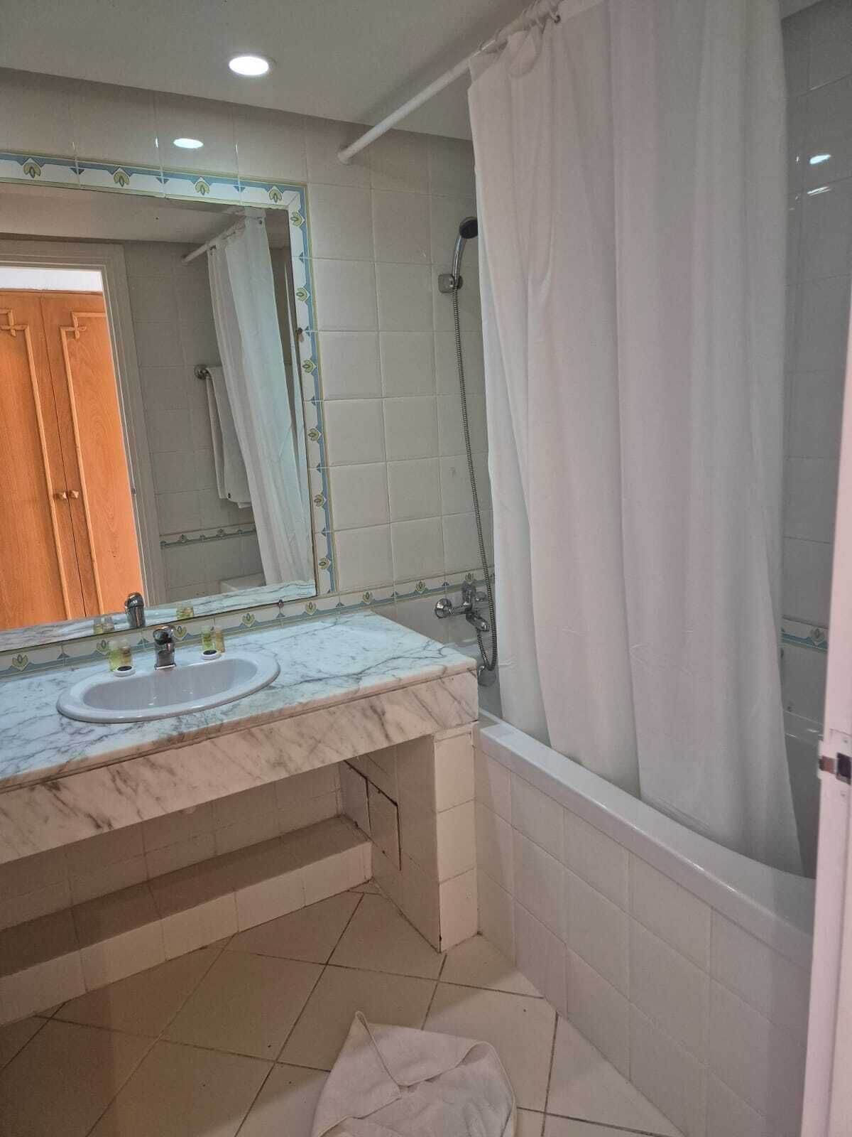 A bathroom with two sinks, a shower, and a mirror with a decorative border.