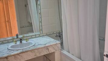 A bathroom with two sinks, a shower, and a mirror with a decorative border.