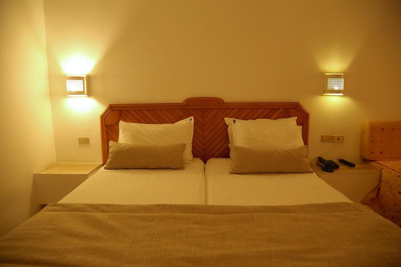 A double bed with a wooden headboard, two bedside tables, and two wall-mounted lights.