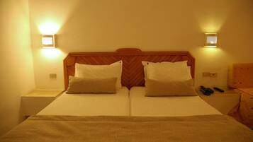 Ein Doppelbett mit hölzernem Kopfteil, zwei Nachttische und zwei Wandleuchten.