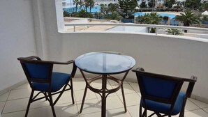 A balcony with a round glass table and two blue cushioned chairs. - Golf Residence- Family Only (Port El Kantaoui)