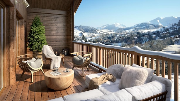Una terraza de madera con un sofá, sillas y una pequeña mesa. Se ve un árbol de Navidad. La terraza ofrece vistas a un paisaje montañoso cubierto de nieve.