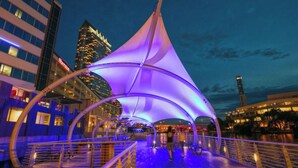 A waterfront promenade with a large, illuminated canopy structure. - Paradise Lust at Paradise Lakes Nudist resort (Lutz)