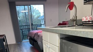 A modern kitchen with a stainless steel refrigerator, white cabinetry, and a large window providing a view of the outdoors. - Paradise Lust at Paradise Lakes Nudist resort (Lutz)