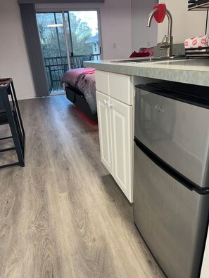 Una cocina moderna con refrigerador de acero inoxidable, armarios blancos y un ventanal con vistas al exterior.