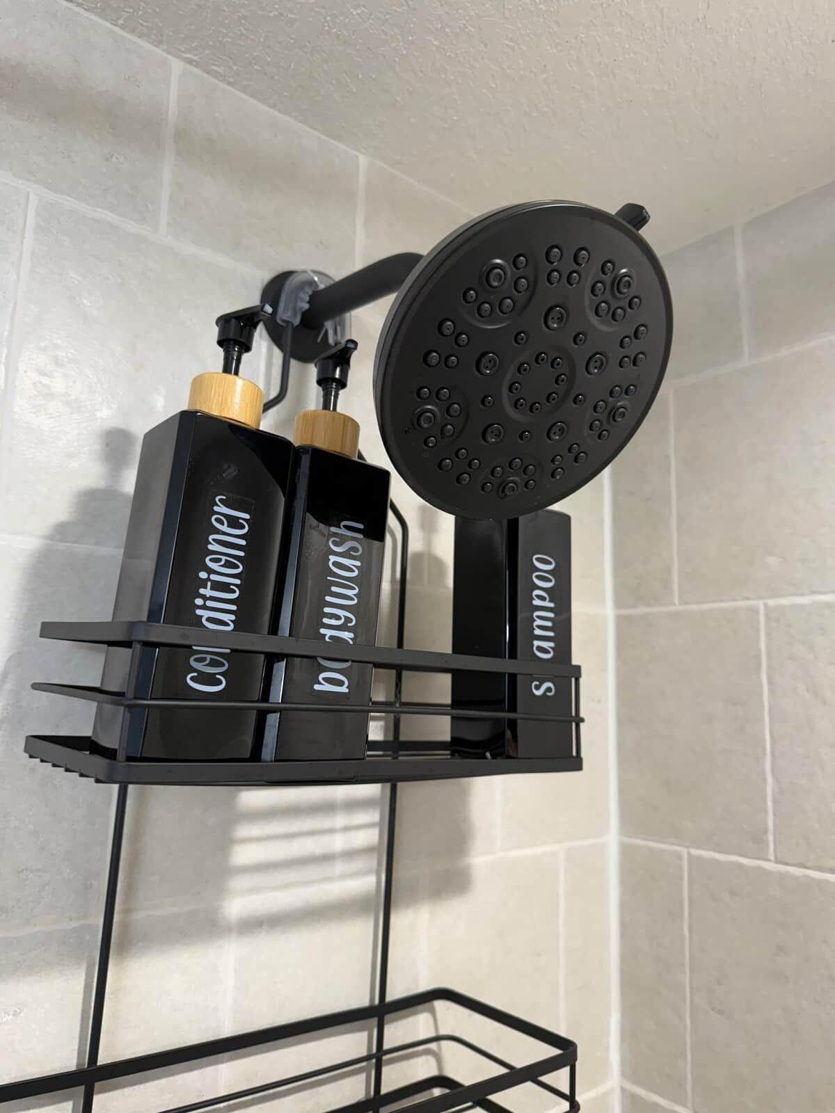 A black showerhead mounted on a wall with a black metal shelf holding two bottles labeled 'Colditor' and 'Balm'.