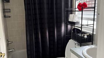 A bathroom with a bathtub, toilet, and a shower curtain.