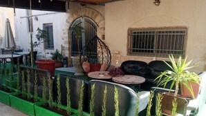 Uma área externa com mesas e cadeiras, uma cadeira suspensa e plantas em vasos.