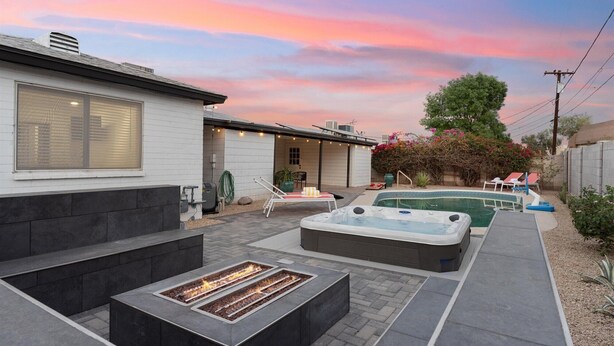 Un patio trasero con jacuzzi, una fogata y una piscina.