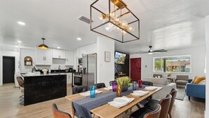 Una cocina moderna con armarios blancos, una isla de mármol negro y electrodomésticos de acero inoxidable.