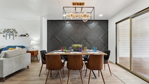 Un comedor moderno con una pared geométrica oscura, una mesa de madera y cuatro sillas.