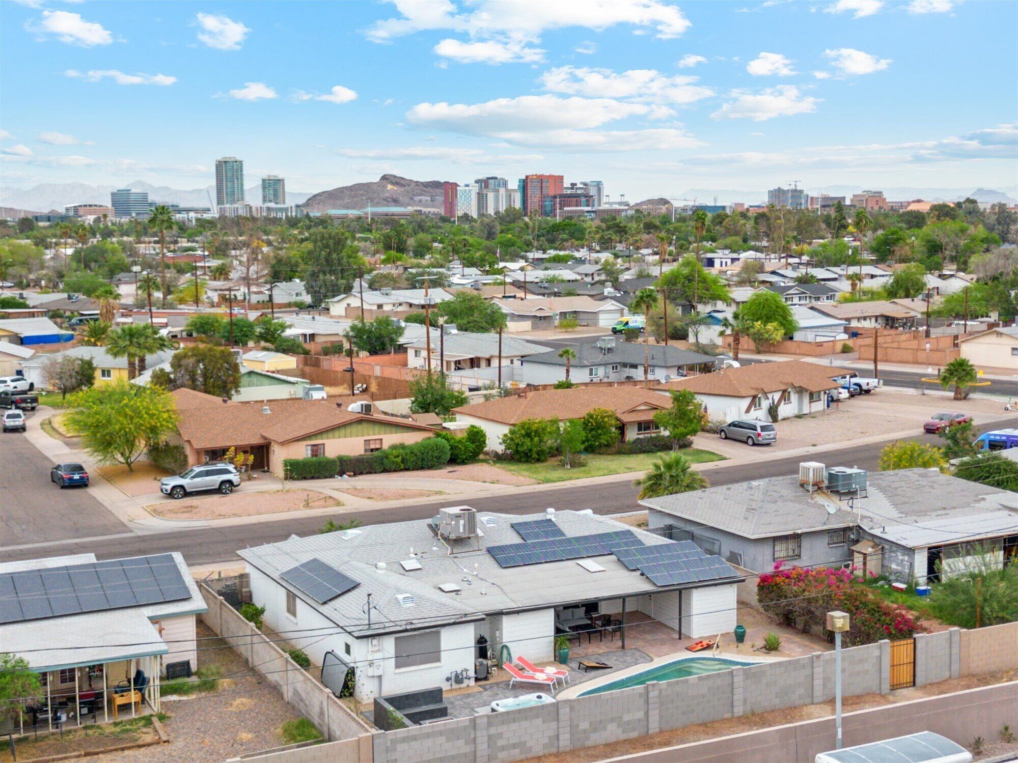 A residential area with houses, a swimming pool, and solar panels on rooftops.