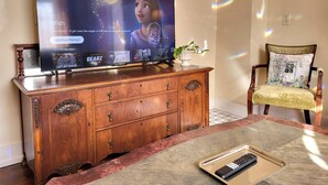 A television on a wooden cabinet with a remote control on a table.