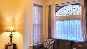 A cozy living room with a leather sofa, a small table, a lamp, and a stained glass window.