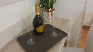 Un tavolino con una bottiglia di vino, due bicchieri e una pianta in vaso.