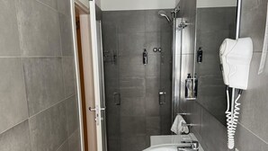 Un bagno moderno con doccia, lavandino e asciugacapelli.
