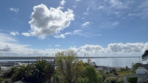 A coastal town with a view of the sea, buildings, and a prominent cloud in the sky.
