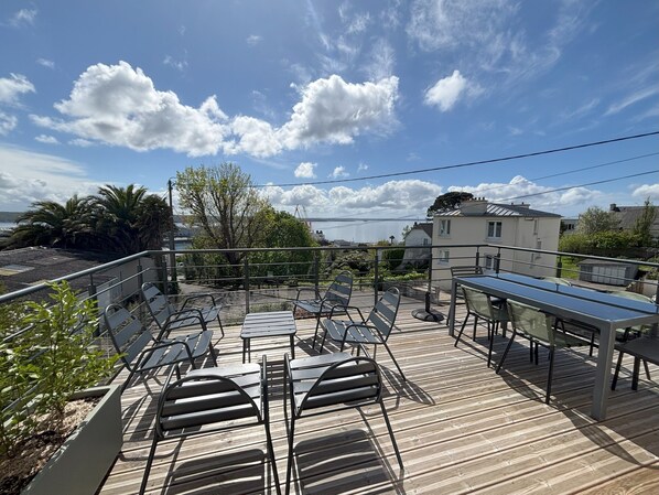 A wooden deck with outdoor seating, overlooking a body of water and a residential area. - Sea view house with terrace (Brest)